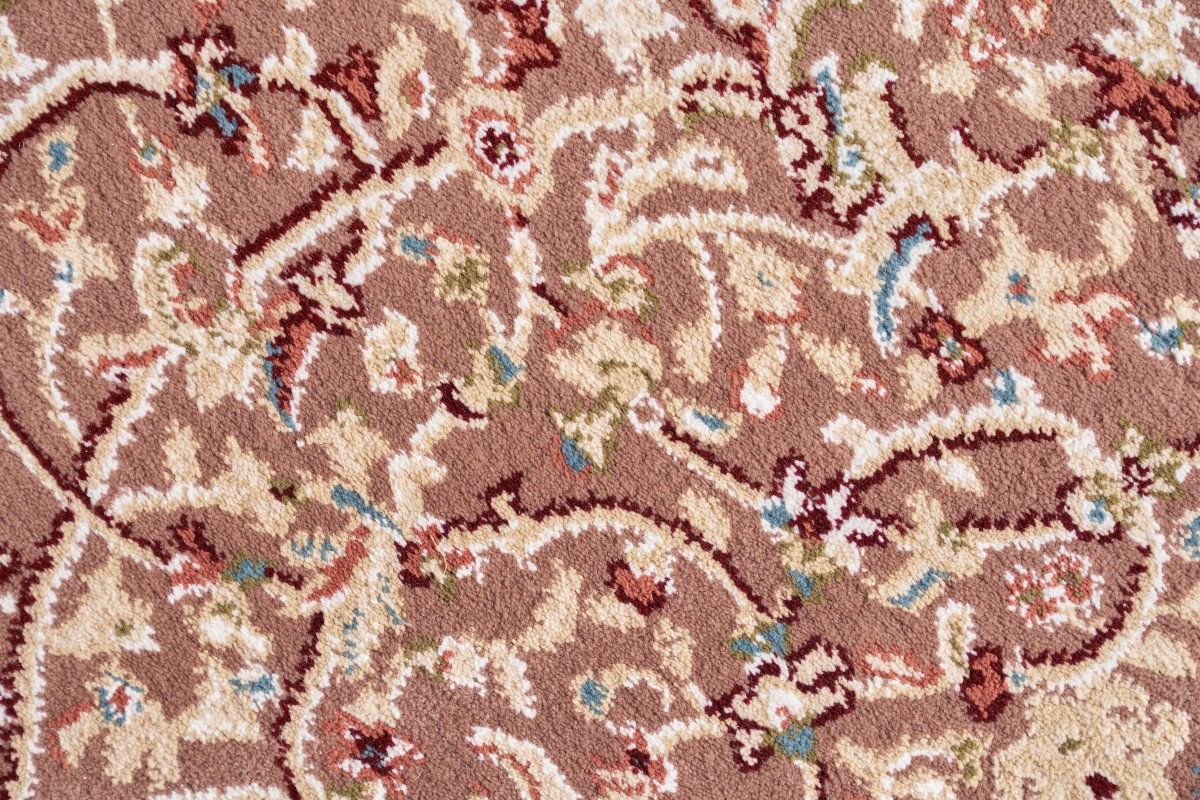 A close-up view of a rug care expert demonstrating how to revive a shaggy rug by gently brushing the matted, flat pile to restore its original fluffy texture.