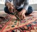 Master artisan performing hand-knotted Persian rug repair to restore unraveled fringes and foundation fibers.