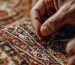 Textile artisan carefully re-weaving damaged wool knots onto an antique foundation for an oriental rug repair near me service.
